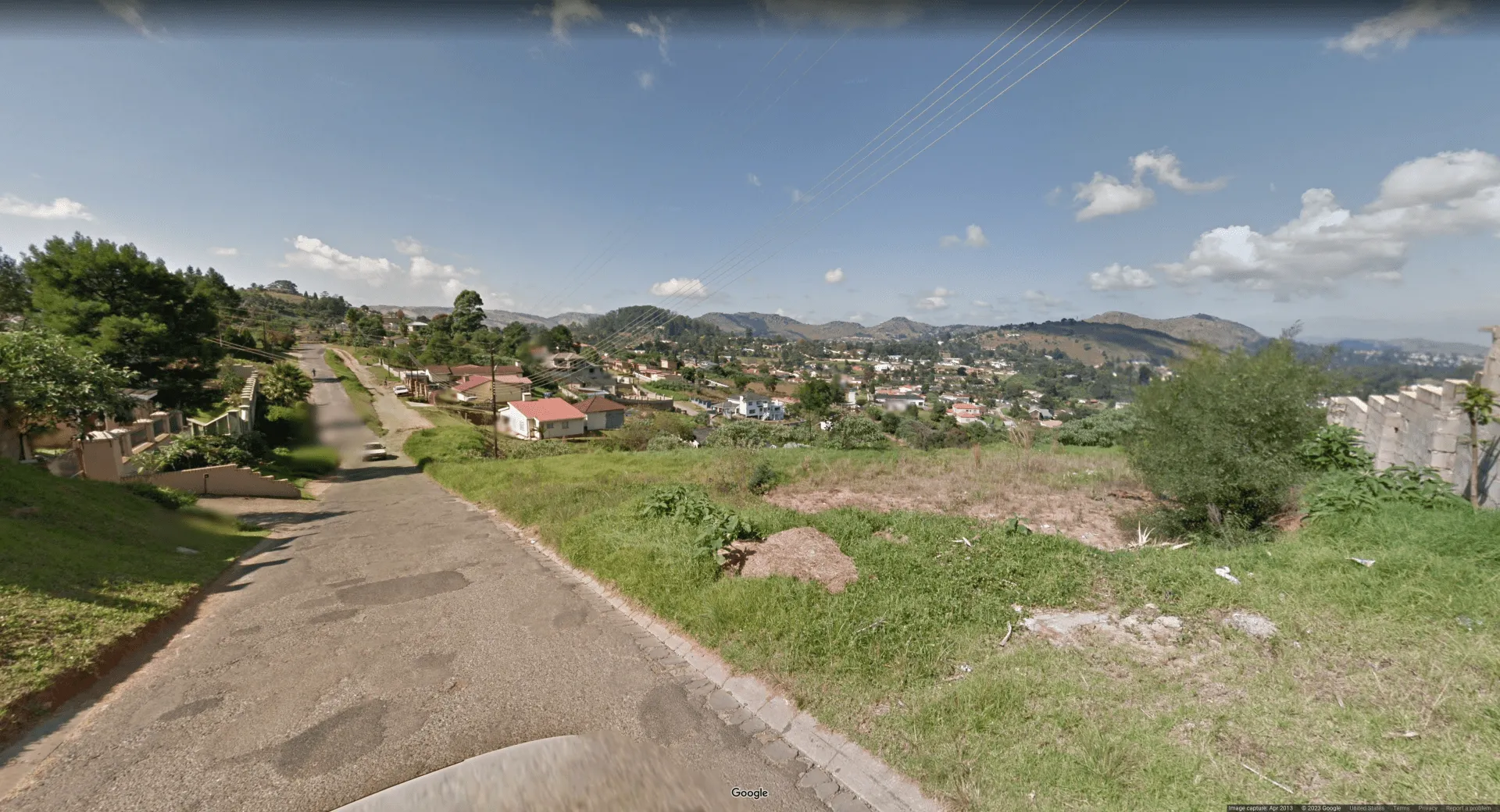 Picture of a hilly region with paved roads and scarce foliage. The houses have red-tiled roofs